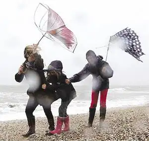 英国近日遭遇强风天气,几位行人顶风艰难行走.(图片来源:扬子晚报)