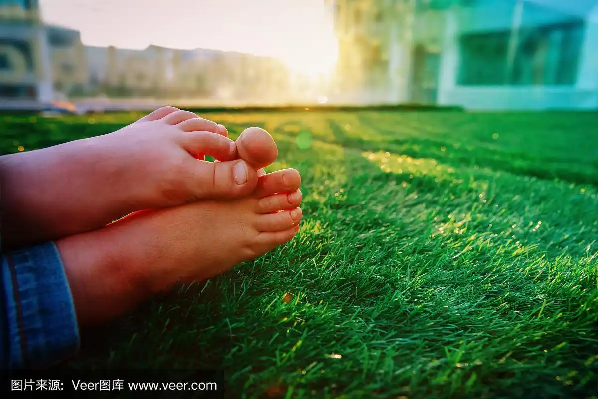 夏天在城市-孩子们赤脚在城市背景的草地上