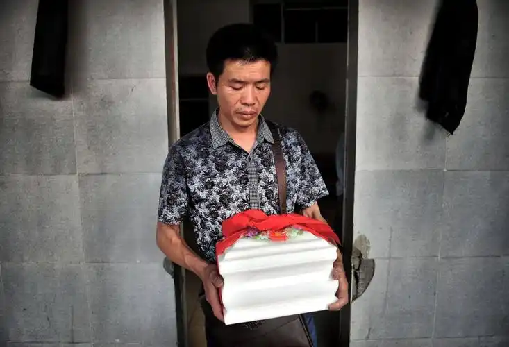 吴明抱着小婷的骨灰离开火化场.