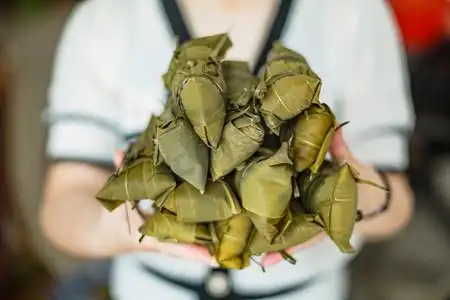 手捧包好的粽子端午节一个人室内手捧摄影图配图