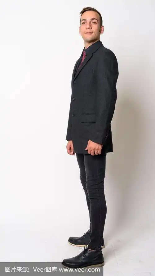 全身拍摄侧面的年轻波斯商人在西装看着相机