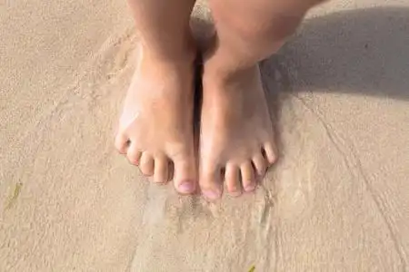 站脚赤脚小子少站在海滩上的沙子,顶视图照片