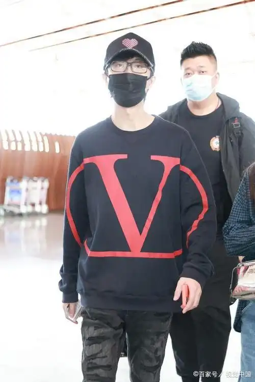 许嵩穿深蓝色卫衣亮相机场 棒球帽上红桃心可爱抢眼