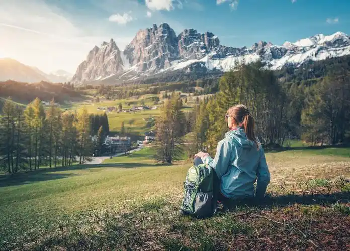 美丽的年轻女子背着背包坐在山上日落时分靠山五颜