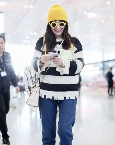 原创热依扎低调现身机场穿斑马毛衣配小黄帽憨态笑容难掩好心情