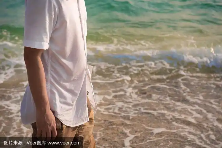 一个带着笔记本电脑的孤独男人正在海边的海滩上散步.