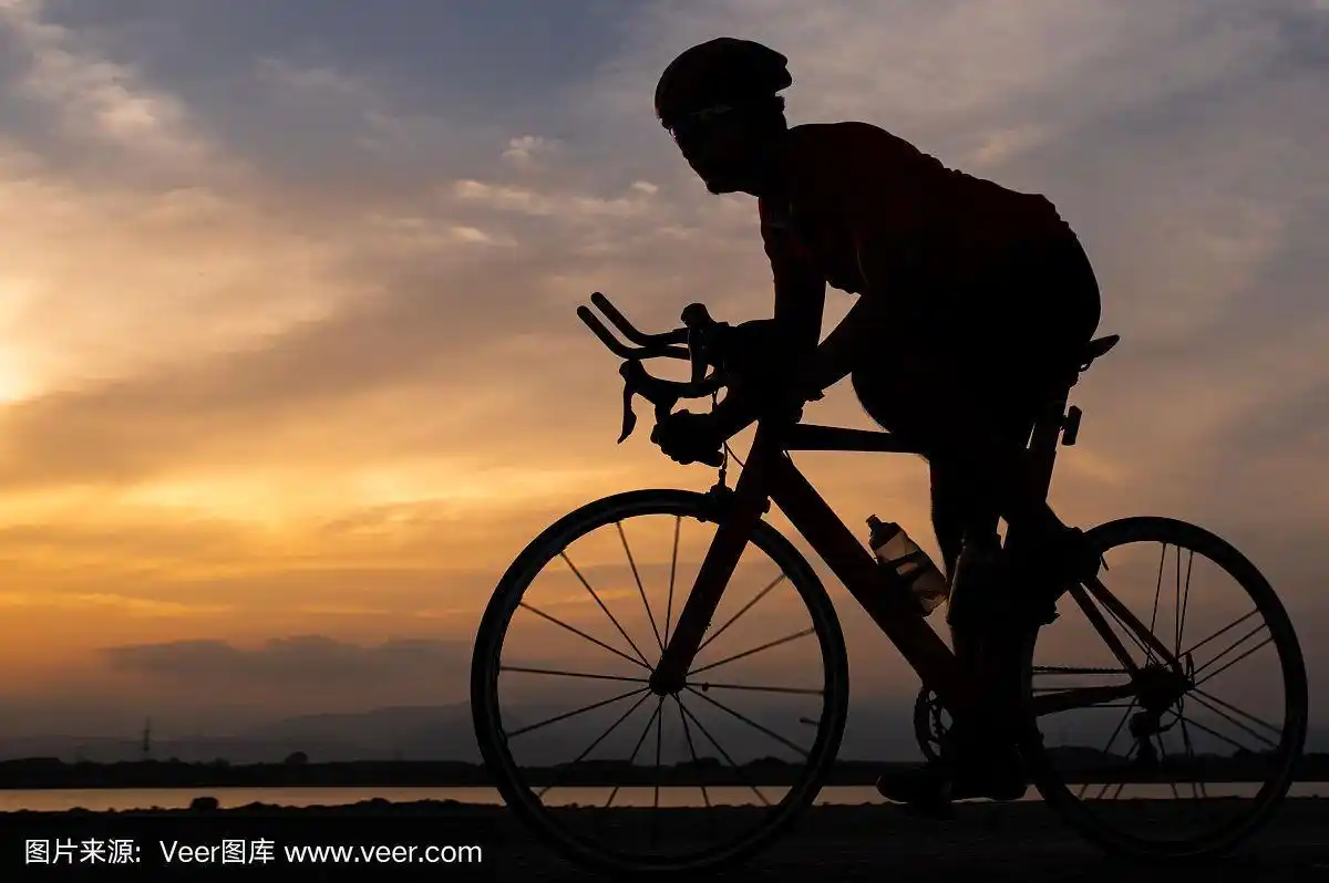 剪影一个骑公路自行车的人在早上骑自行车.