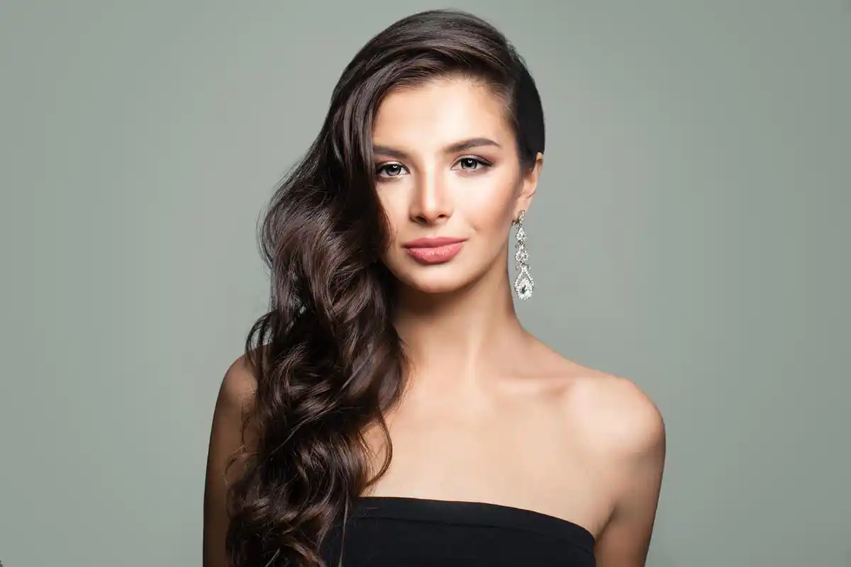 美丽的黑发妇女与长卷曲头发灰色背景.