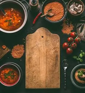 健康素食扁豆菜肴的切板食物背景在深色厨房餐桌背景上,配料,顶视图.