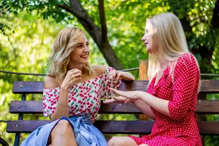 两个迷人的金发女朋友在公园里聊天和拥抱.