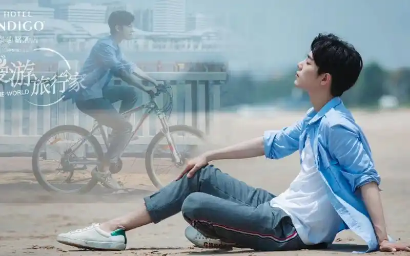 肖战穿着拖鞋在沙滩上,被沙子烫到双脚跳跃