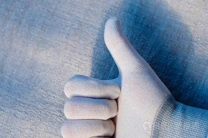 白色标牌中的一只手在织物结构的背景上显示了质量标记