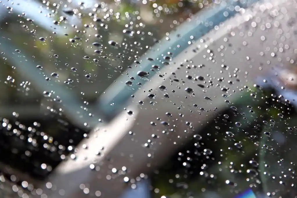 前面的汽车的挡风玻璃上的水珠.