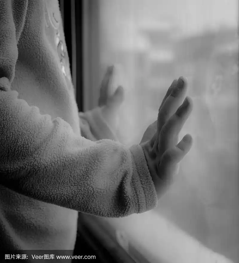 孩子把手放在玻璃上望着窗外