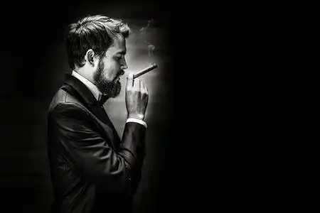 男子吸烟雪茄黑色和白色的胡子吸烟的雪茄绅士在西装的肖像照片