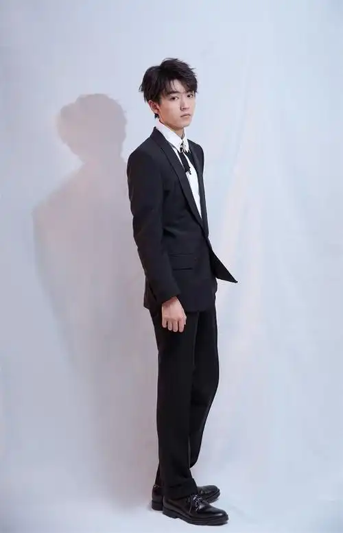 王俊凯身着黑色西装搭配花叶领结亮相,整体造型凸显绅士魅力又不失