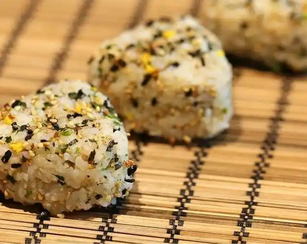 三,杂粮芝麻饭团3,剪一片大小适中的长方形紫菜,沿饭团两侧包住就可以