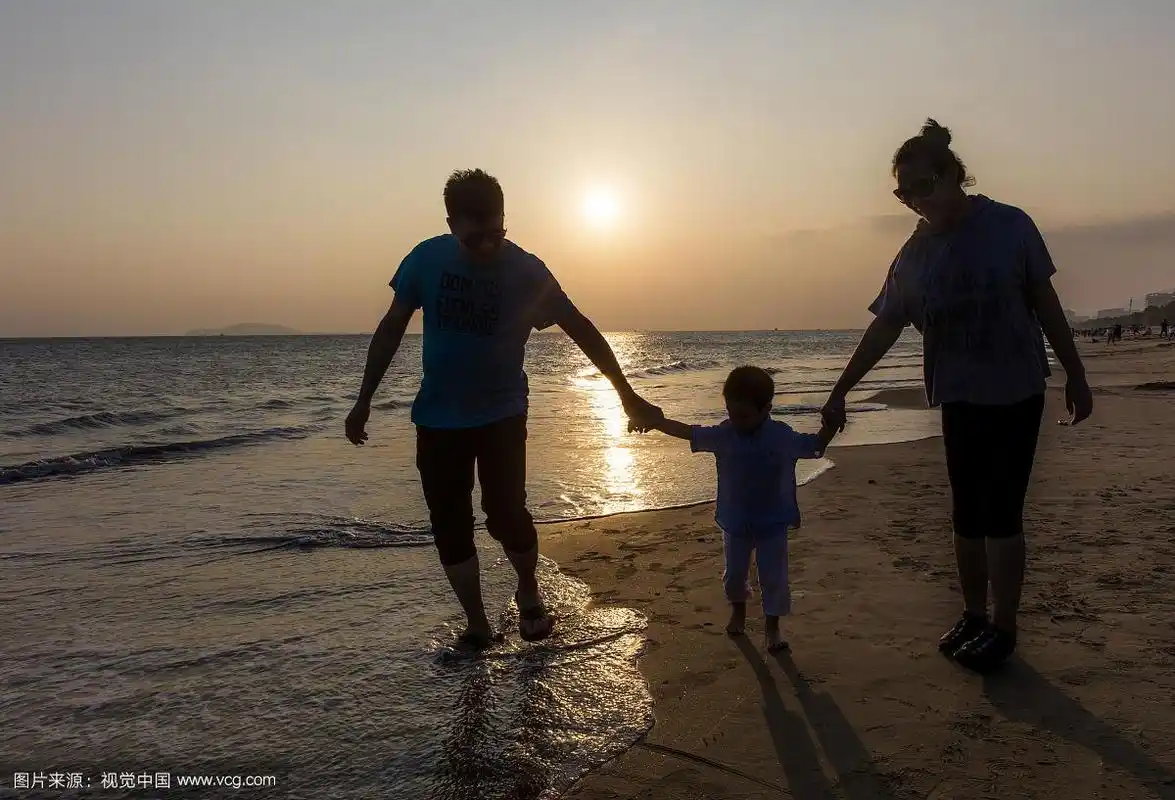 一家三口日光时分在海滩散步