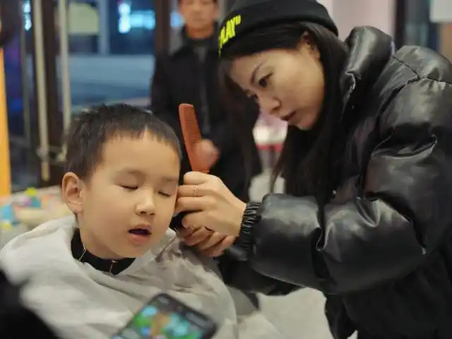 2月21日,两江新区湖山路,小朋友正在理发店内剪头发.