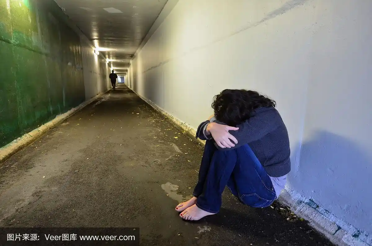 女人悲伤地蹲在隧道里