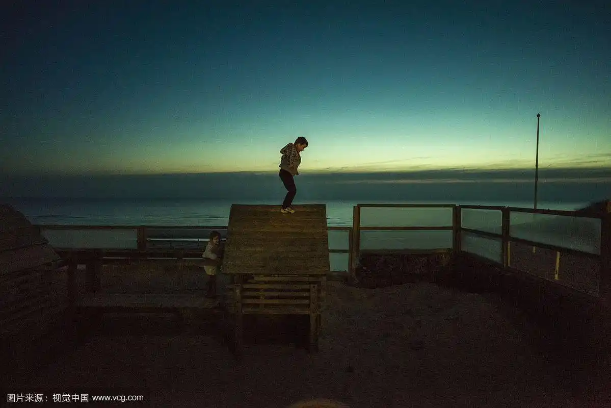 黄昏时分,小男孩站在木屋顶上