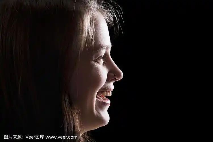 漂亮的女孩笑在黑色背景的侧面