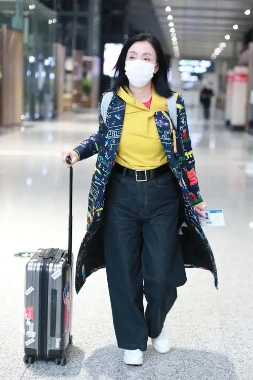 小陶虹穿黄色卫衣搭配风衣现身机场一袭穿搭简约不失格调