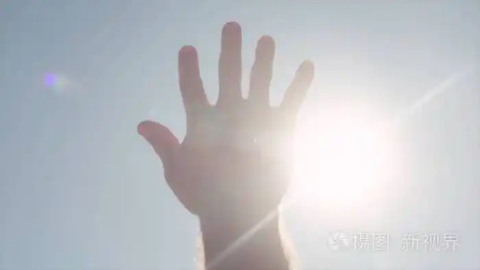手的特写镜头伸手去拿太阳股票明亮的阳光穿过伸出的手的手指向天空