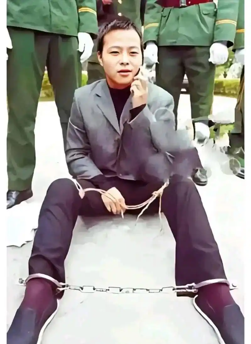 照片中的死刑犯身上绑着法绳,脚上戴着铁链,右手夹着香烟,左手拿着