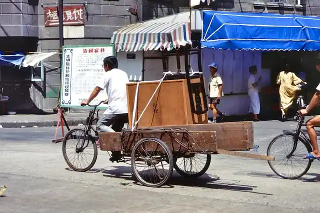 1992年中国历史老照片:图为一个男人骑着三轮车到大街上卖盒饭,是一个