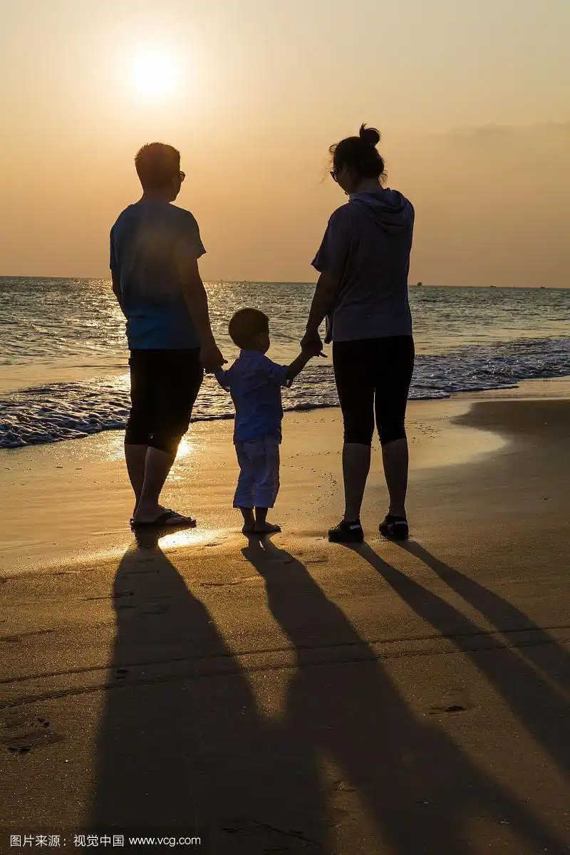 一家三口日光时分在海滩散步
