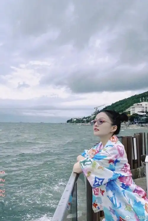 张韶涵在社交平台上被晒出游玩照,她在海边度假随拍,彩色印花衬衫套装