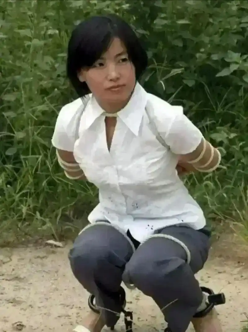 90年代,女犯人被执行枪决时的一张照片,她身穿白色衬衣,蹲在地上,被五