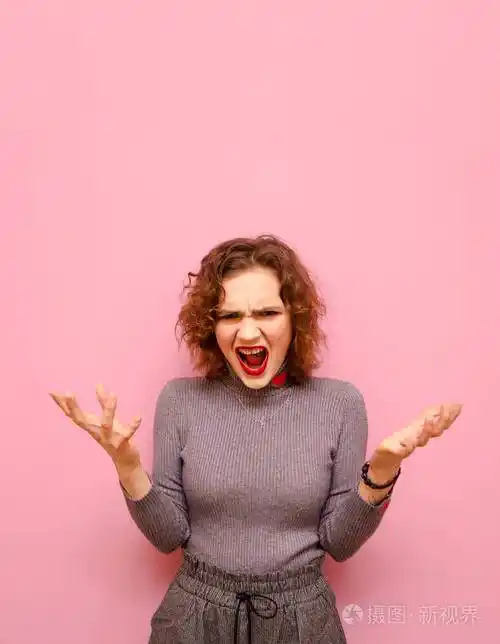 一个情绪激动的女孩穿着时髦的休闲服卷发粉色背景看