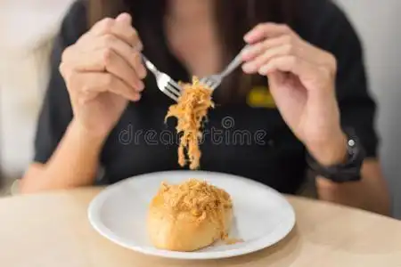 女人吃面包采用白色的盘子照片