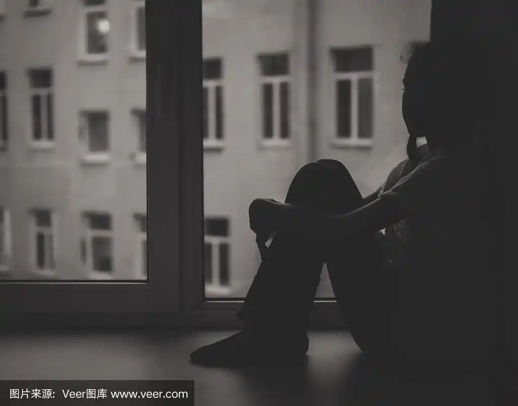 悲伤的小女孩坐在窗边.黑色和白色.