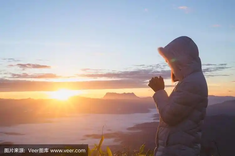 清晨祈祷,女人在清晨日出的背景上双手合十祈祷.