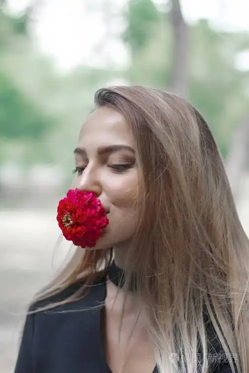 有一朵花在她嘴里的优雅女人.花红色.那个女孩看上去令人惊叹.