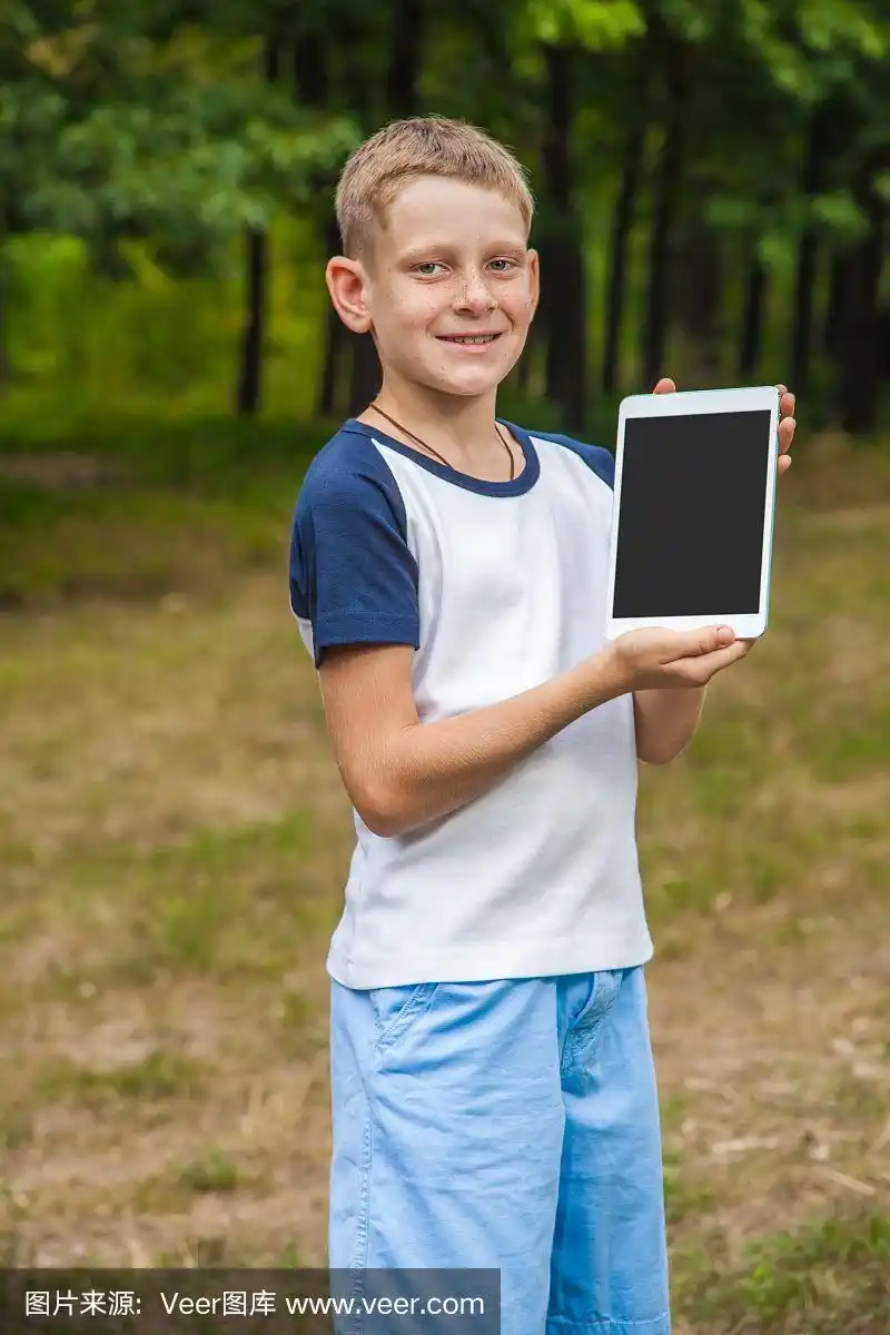 可爱的白人小孩在公园里玩平板电脑.