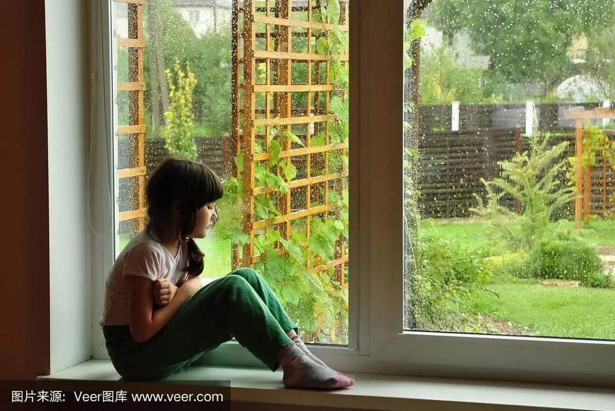 一个年轻的女孩独自坐在窗边