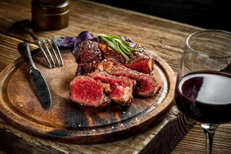 烤红牛牛排和红酒配香草和香料在木桌上