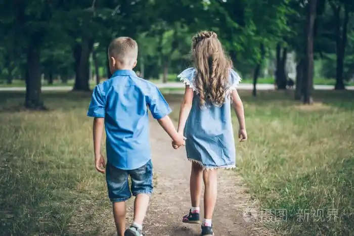 一个小男孩和女孩一起走着,彼此手牵着手