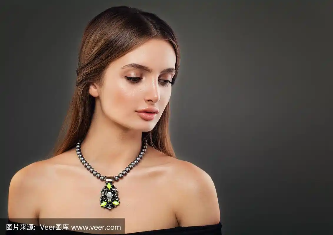 美丽的年轻女子戴着珍珠项链在黑暗的背景