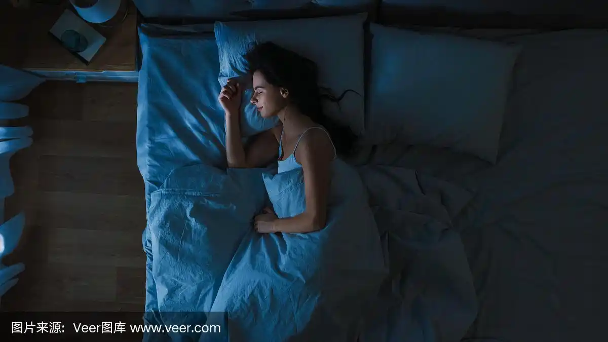 俯视图美丽的年轻女子舒适地睡在床上在他的卧室晚上.