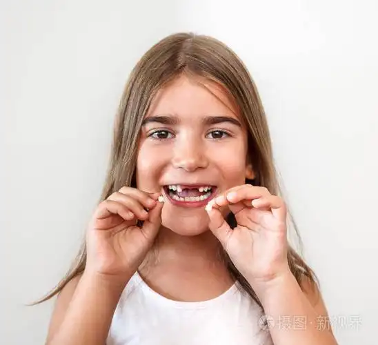 小女孩没有牙齿微笑看着相机和手牵着牙齿