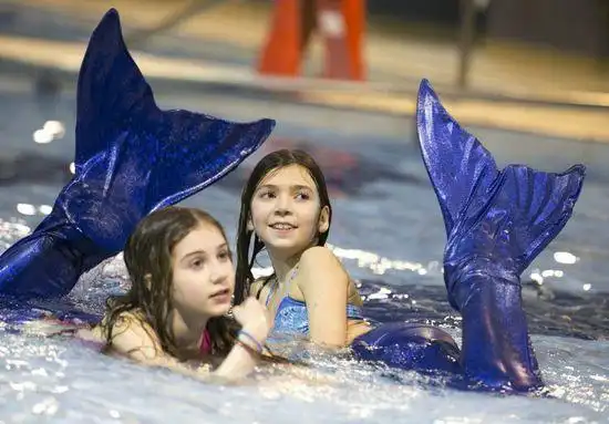 学员们在双腿套上模仿鱼尾巴的美人鱼服装,在水中模仿鱼的各种动作