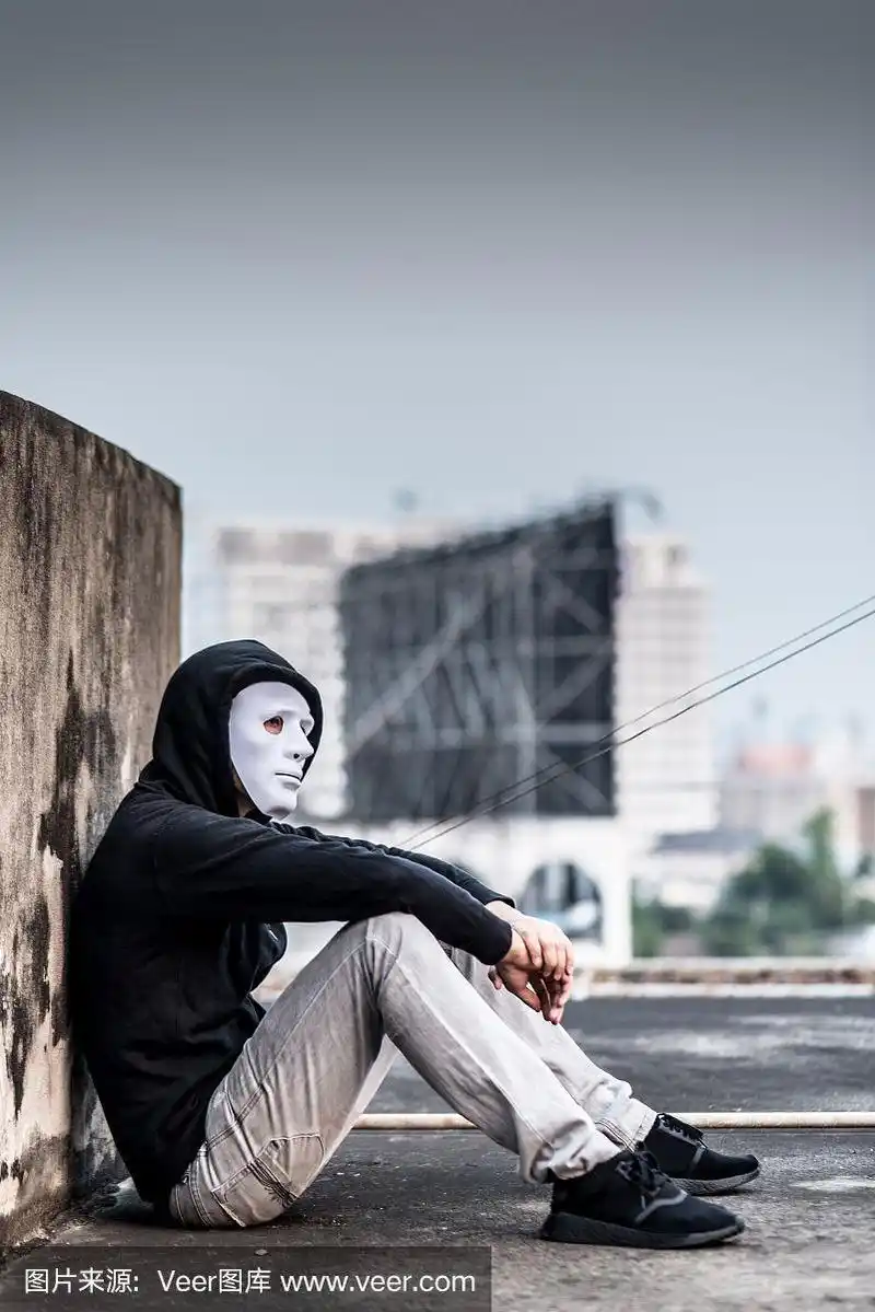 戴着白色面具的神秘男子坐在废弃的建筑里,眼神悲伤
